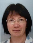 A person with glasses and a blue background
Description automatically generated