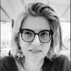 A person wearing glasses and a black shirt
Description automatically generated